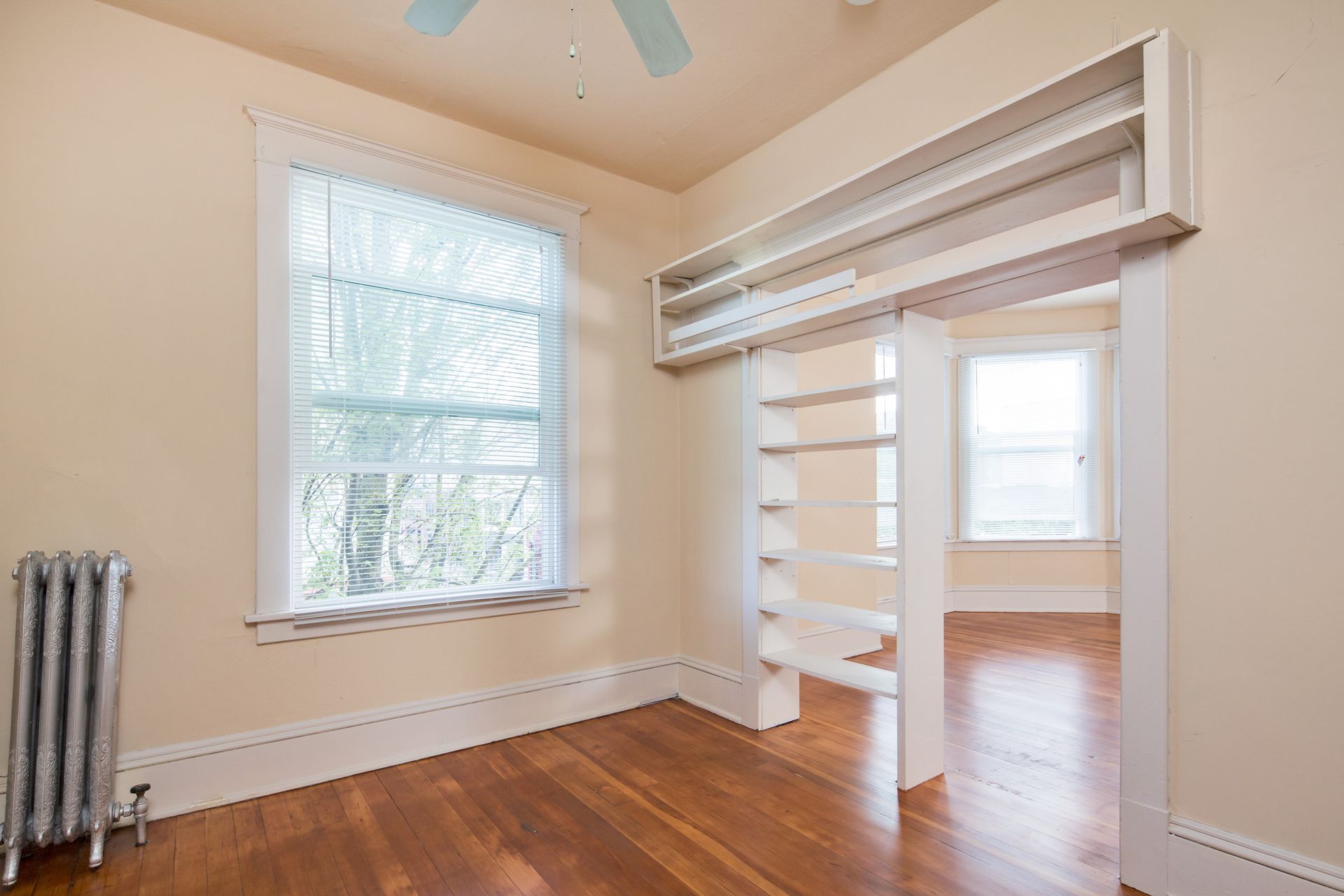 An empty room with hardwood floors and a ceiling fan.