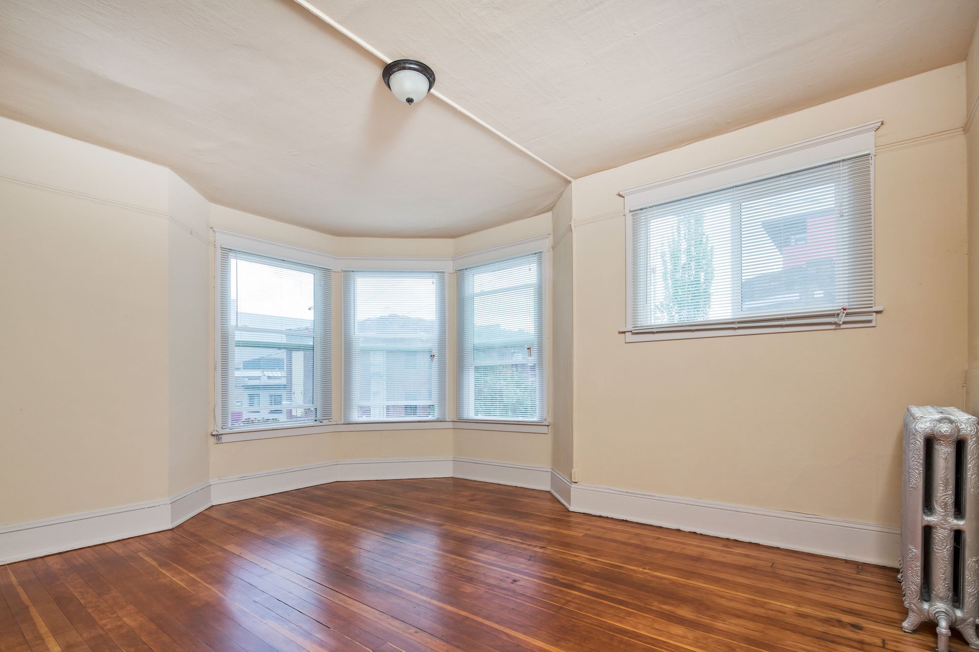 An empty room with hardwood floors and three windows.