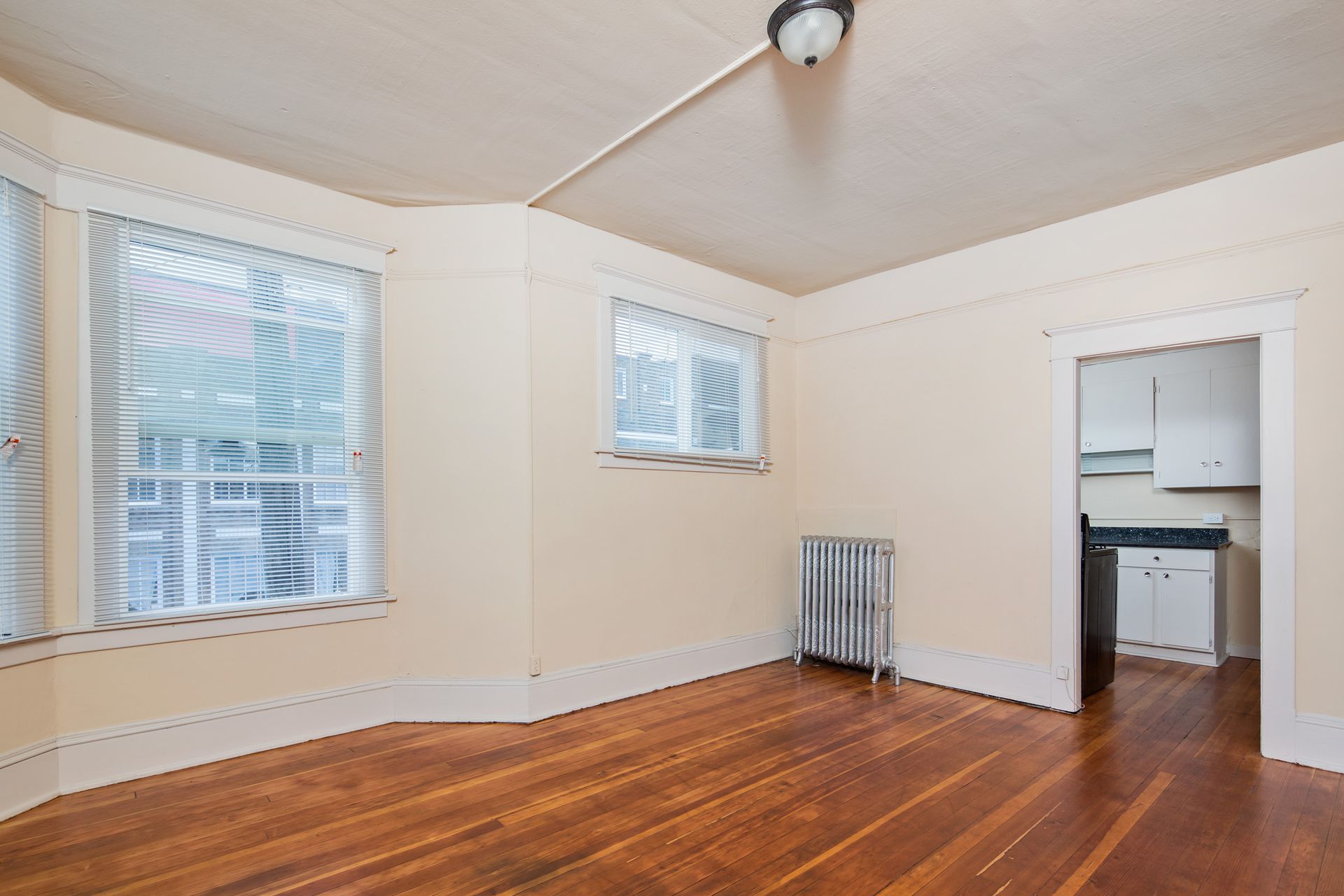 An empty room with hardwood floors and a radiator