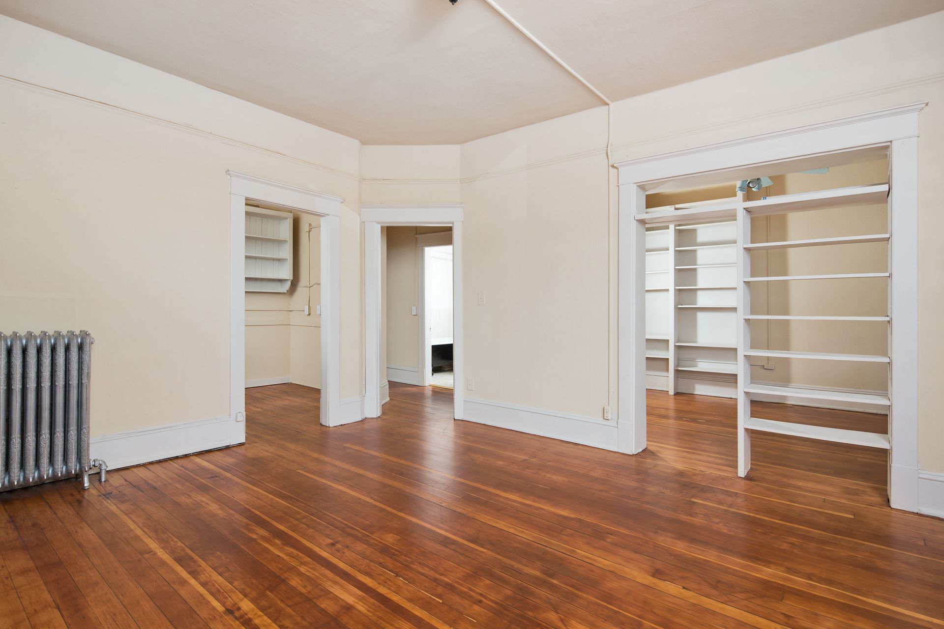 An empty room with hardwood floors and white walls