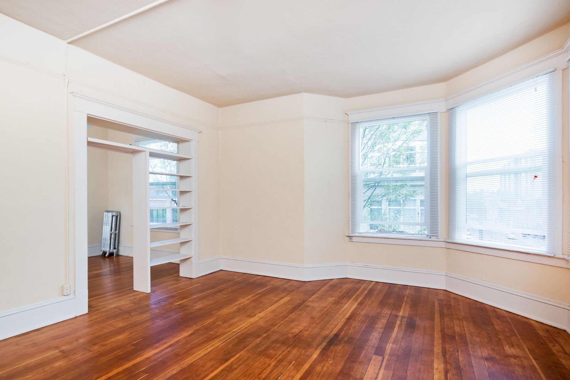 An empty room with hardwood floors and white walls