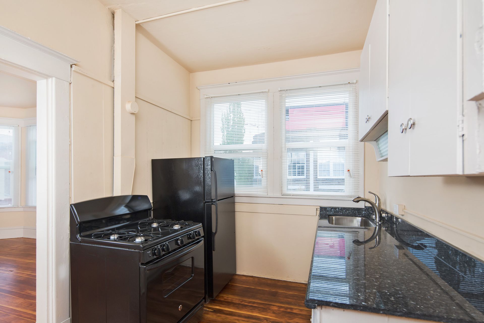 A kitchen with a stove , refrigerator , sink and window.