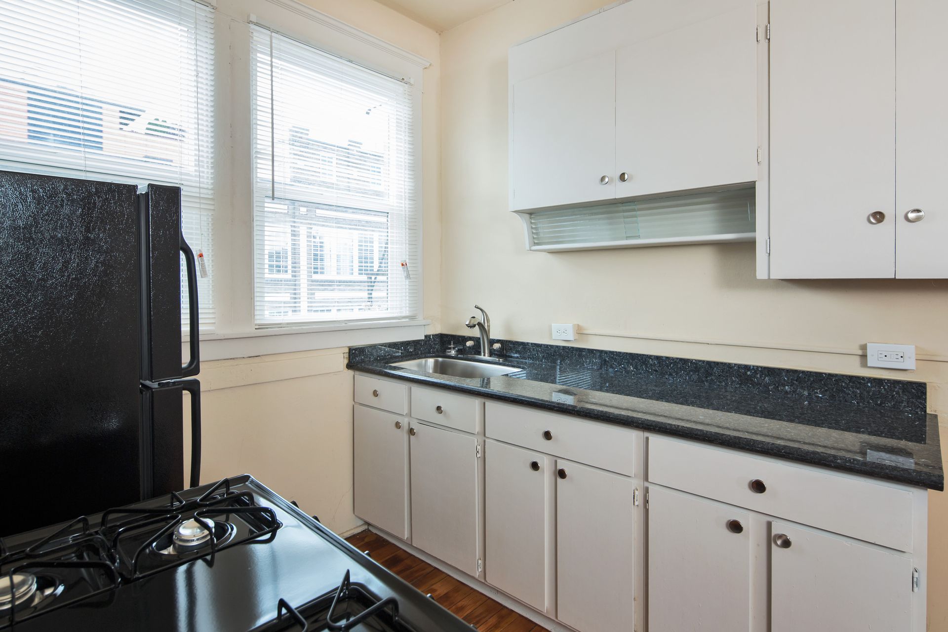 A kitchen with white cabinets and a black refrigerator