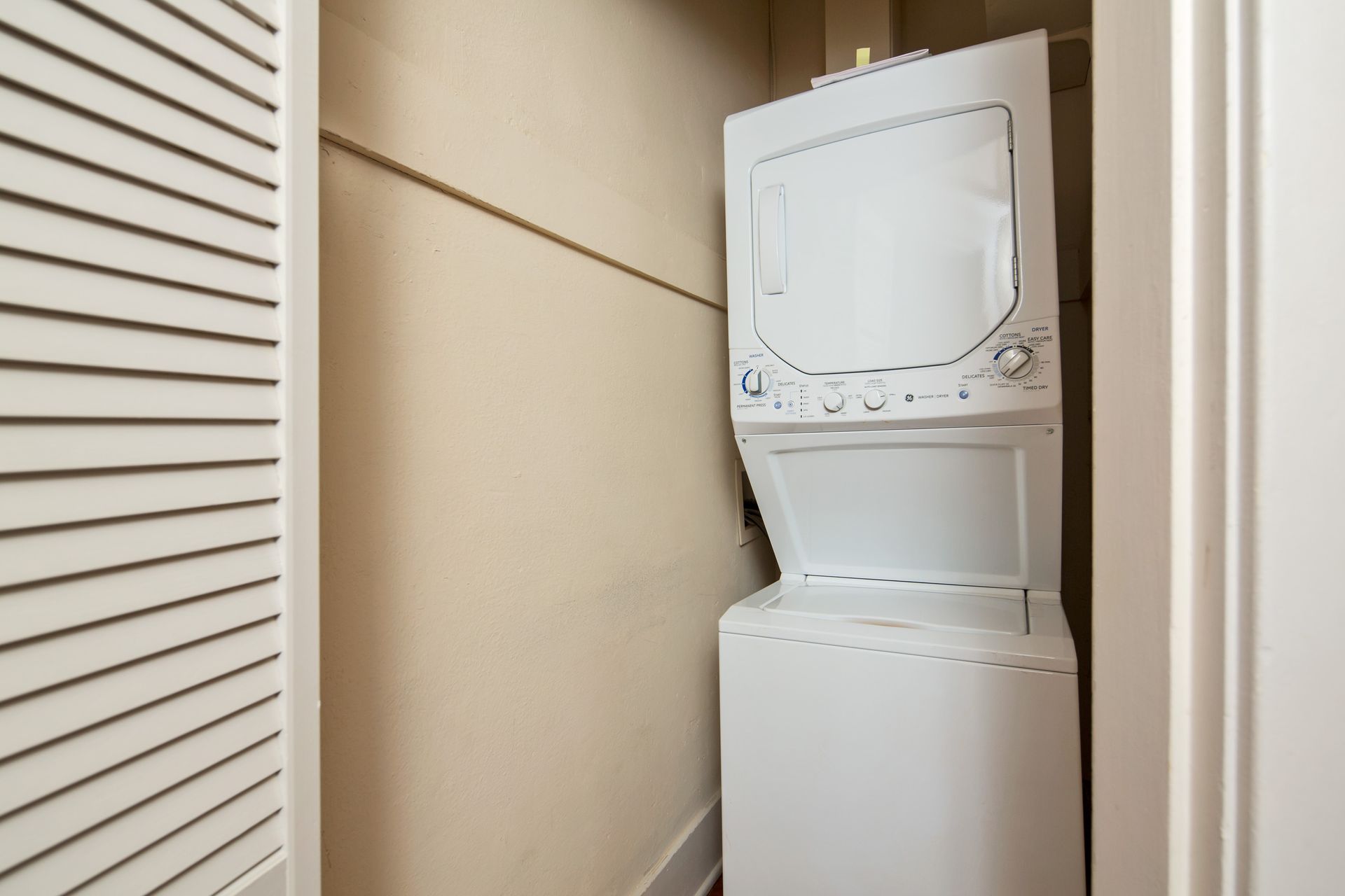 A washer and dryer are stacked on top of each other in a closet.