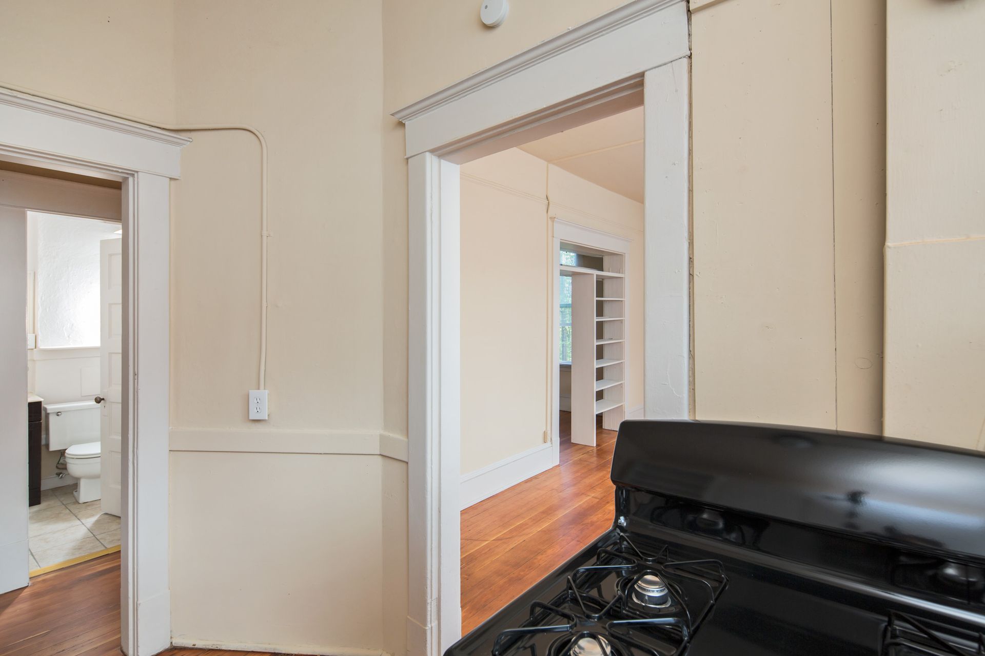 A kitchen with a stove and a doorway leading to a bathroom.
