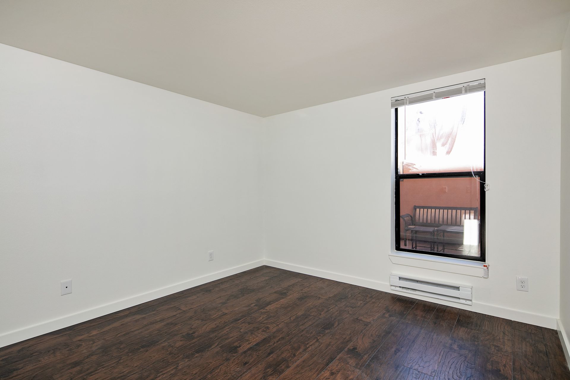An empty room with hardwood floors and a window.