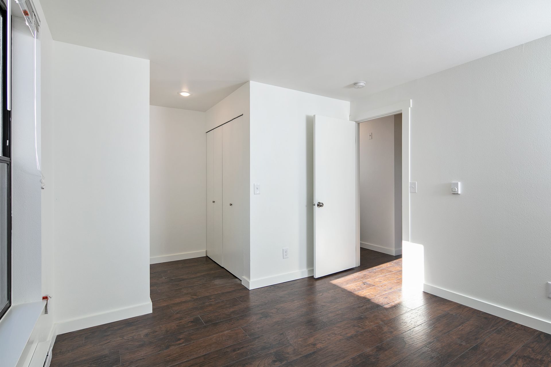 An empty room with hardwood floors and white walls