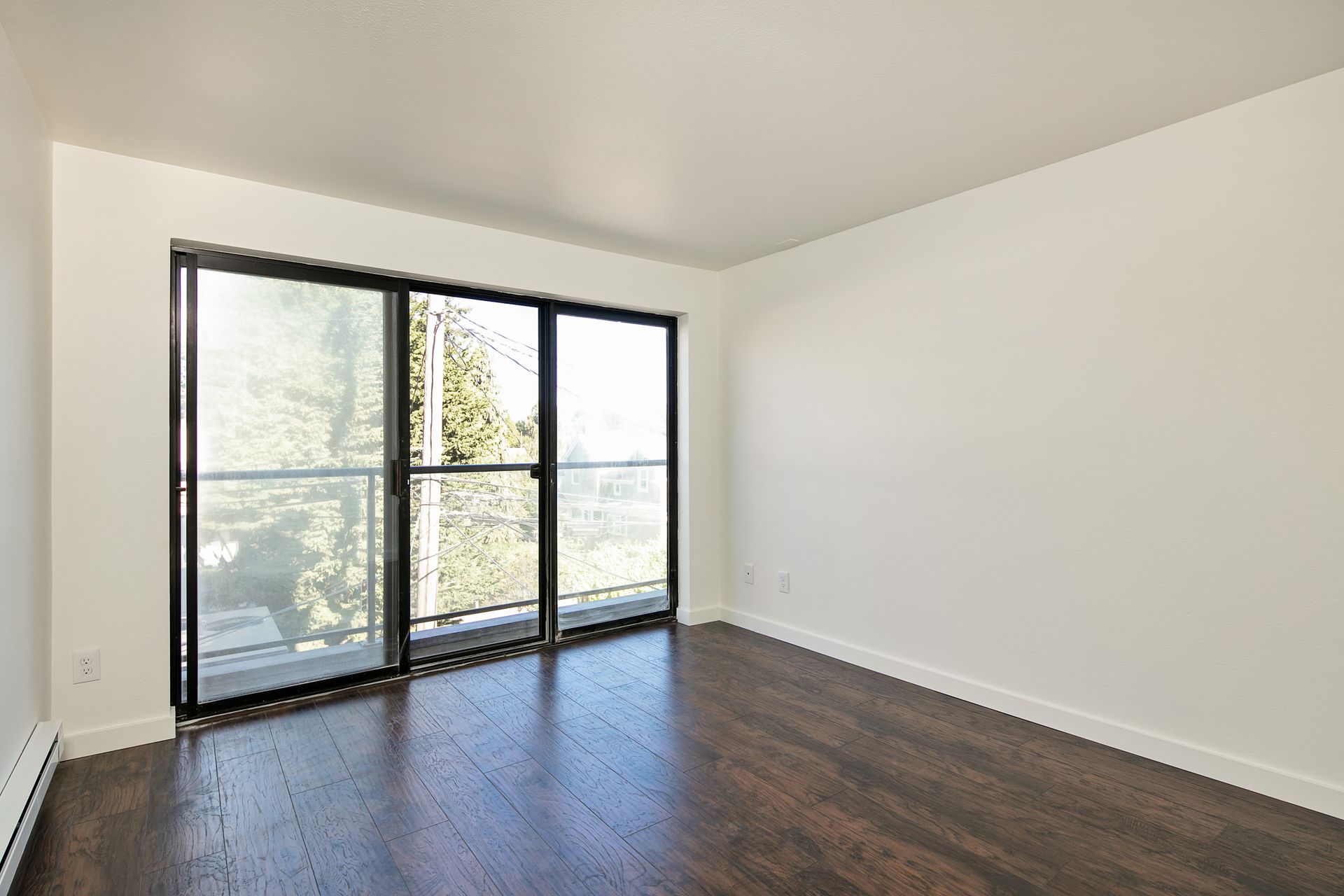 An empty room with hardwood floors and sliding glass doors