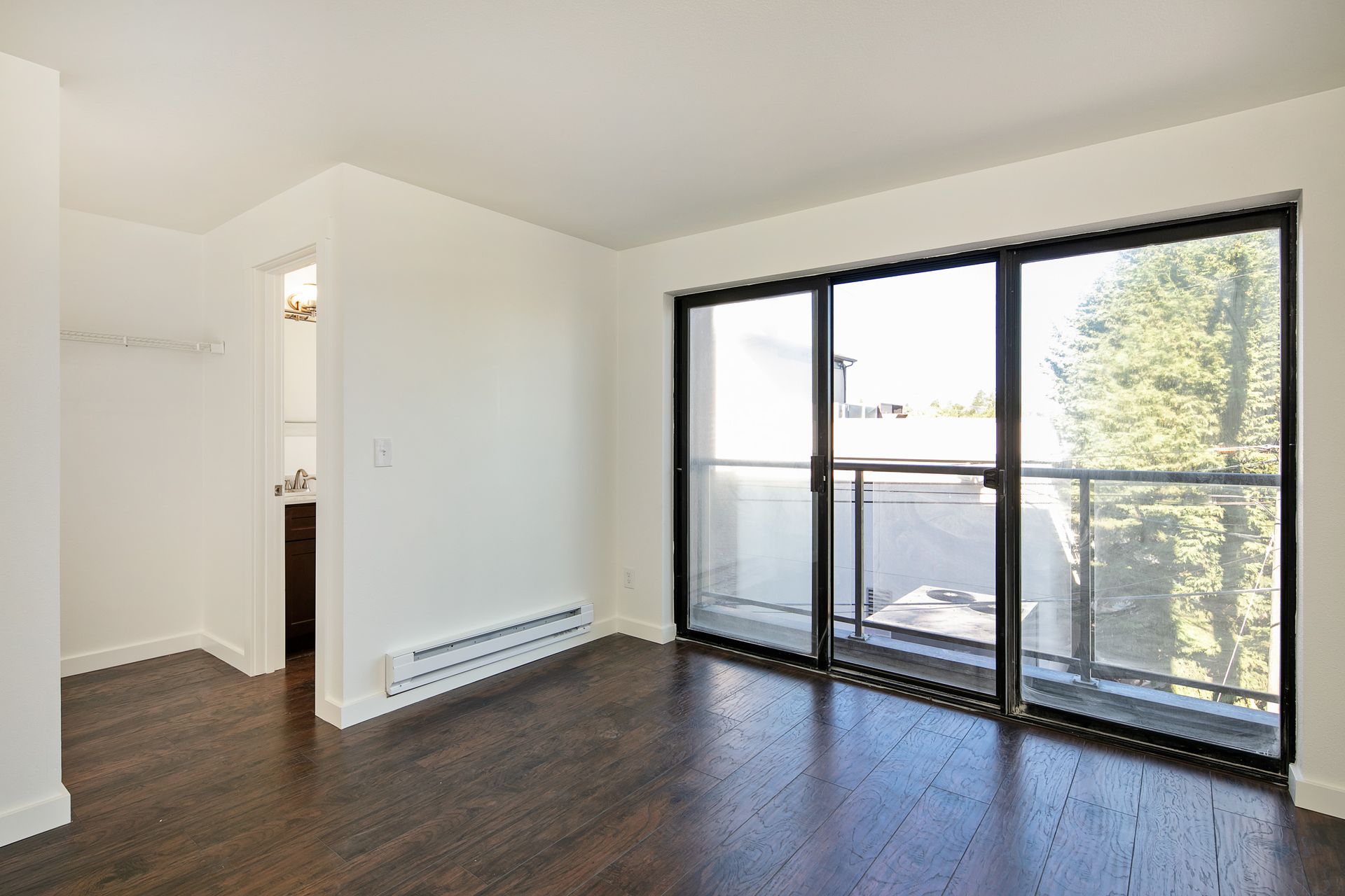 An empty room with a balcony and sliding glass doors