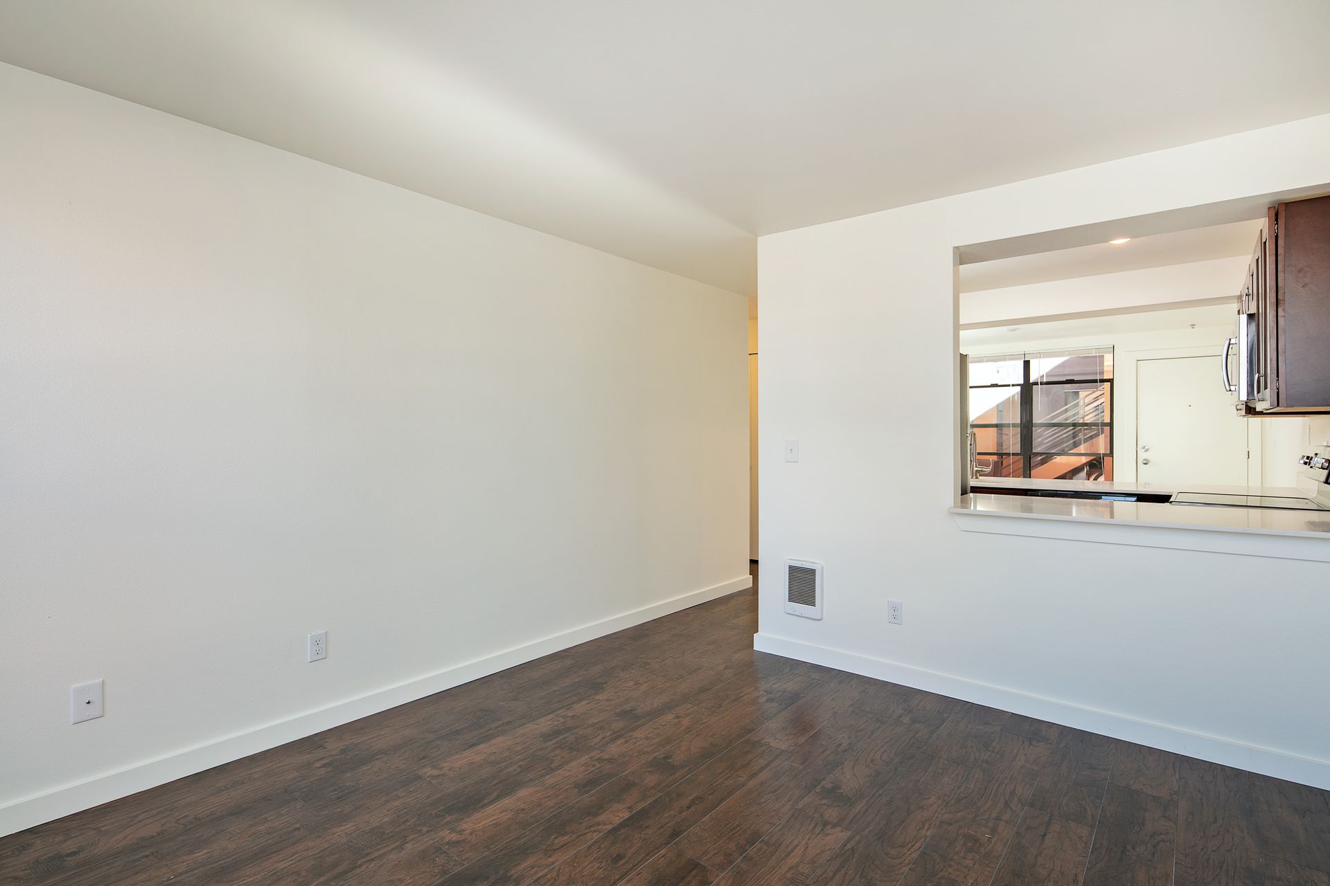 An empty living room with hardwood floors and white walls