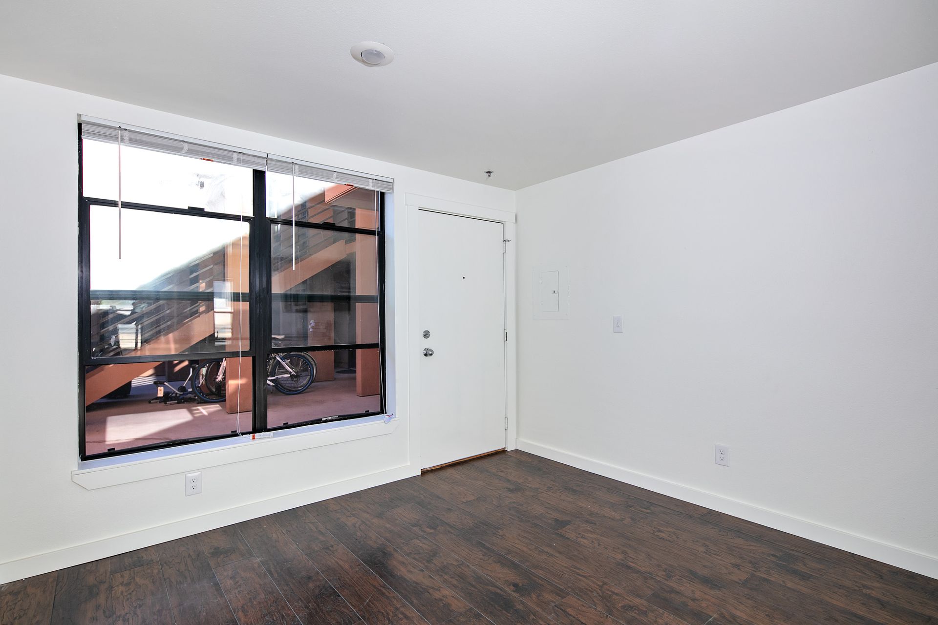 An empty room with hardwood floors and a large window