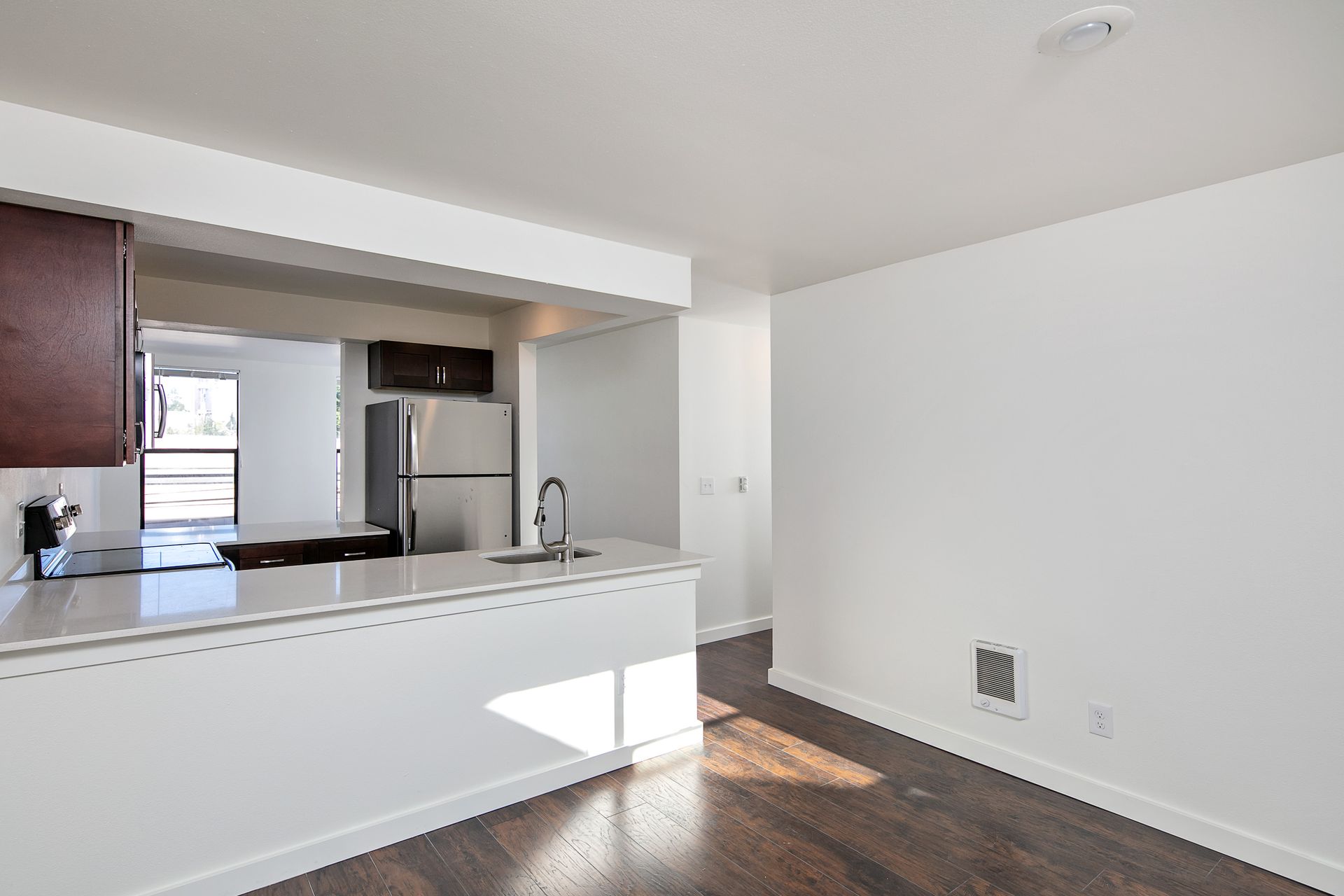 An empty kitchen with a stainless steel refrigerator and a sink.