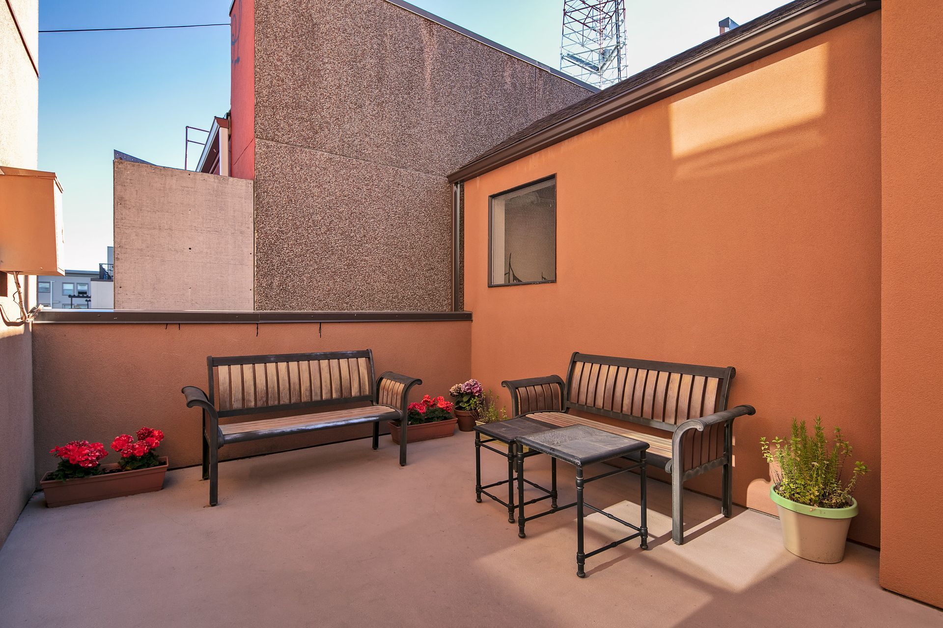 A patio with two benches and a table in front of a building