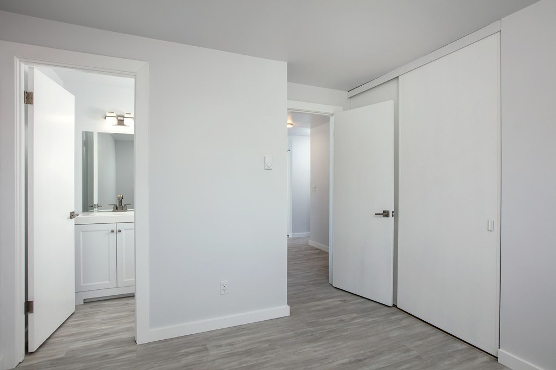 A bedroom with a bathroom and a closet.
