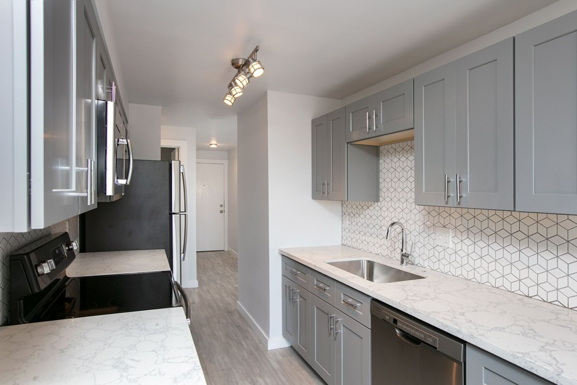 A kitchen with gray cabinets and stainless steel appliances