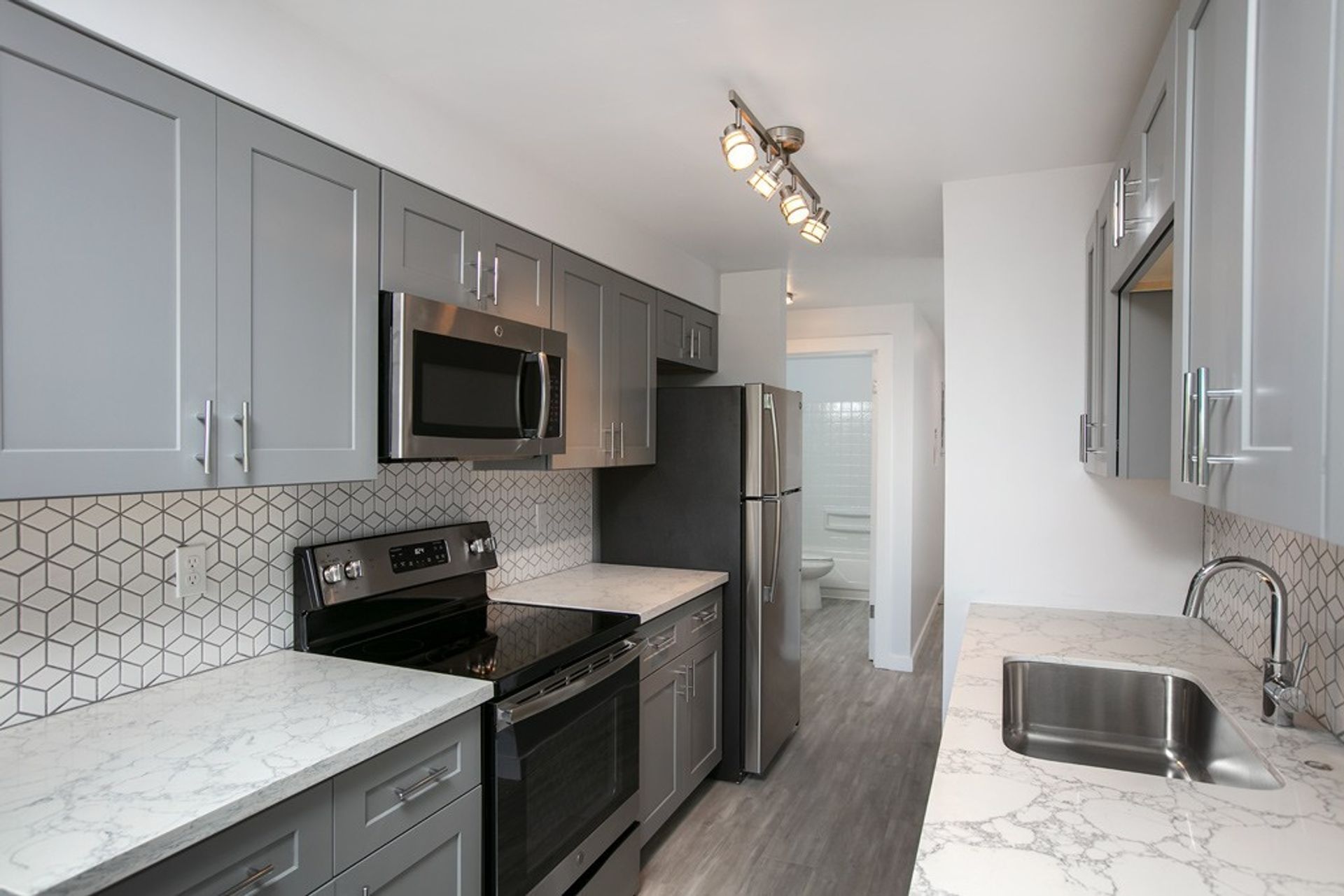 A kitchen with stainless steel appliances and gray cabinets