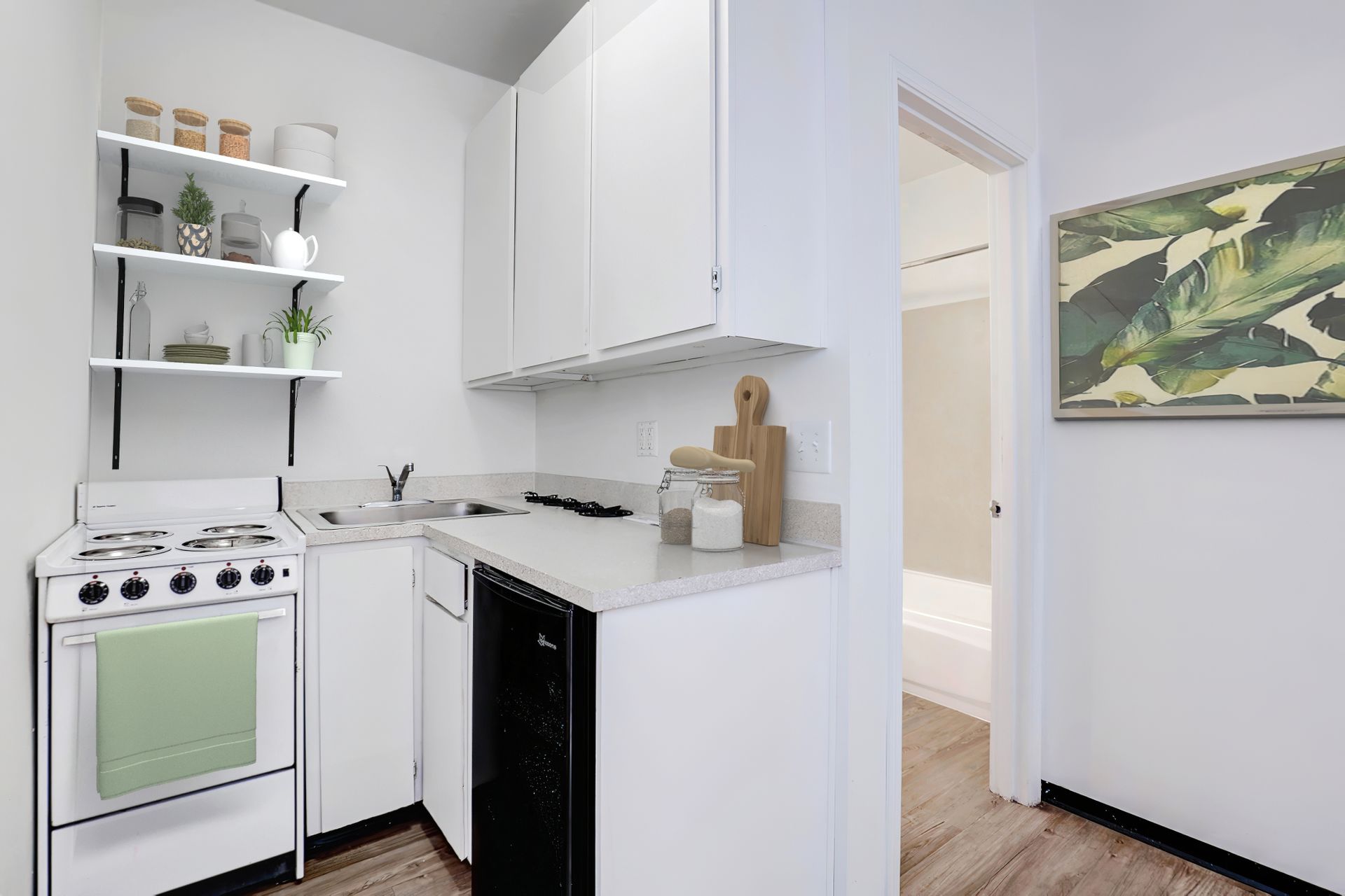 A kitchen with white cabinets , a stove , a sink , and a dishwasher.