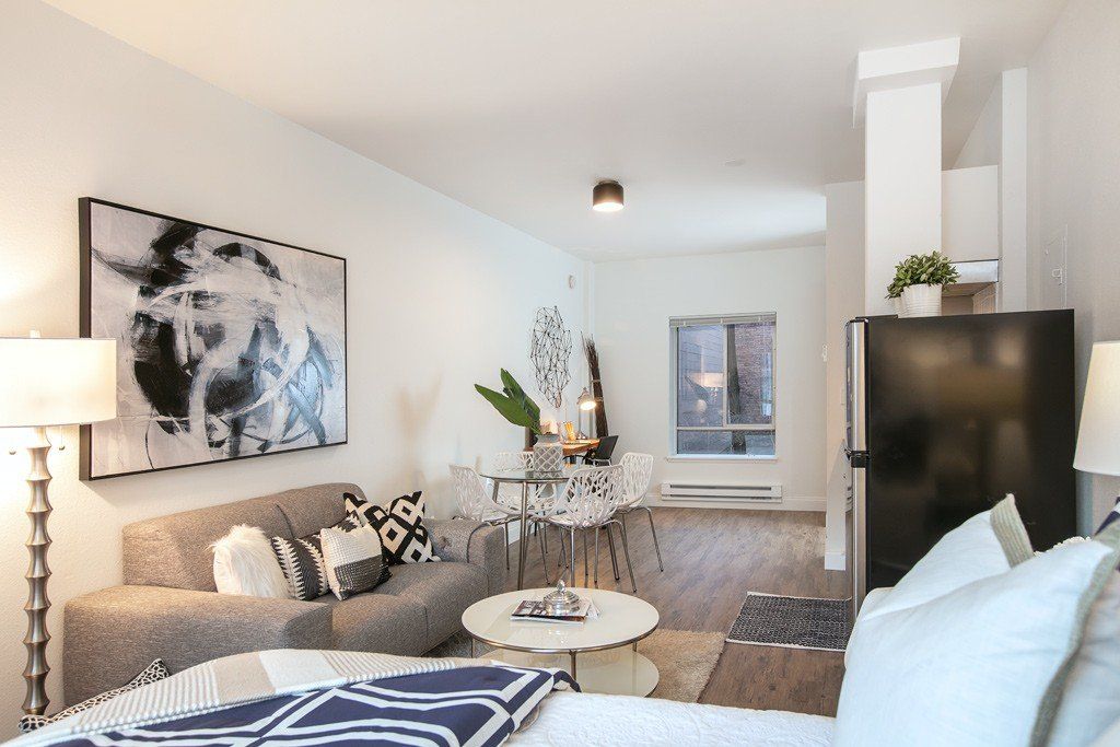 A living room with a couch a table and a refrigerator