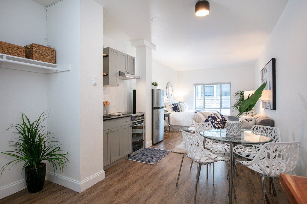 A living room with a dining table and chairs and a kitchen.