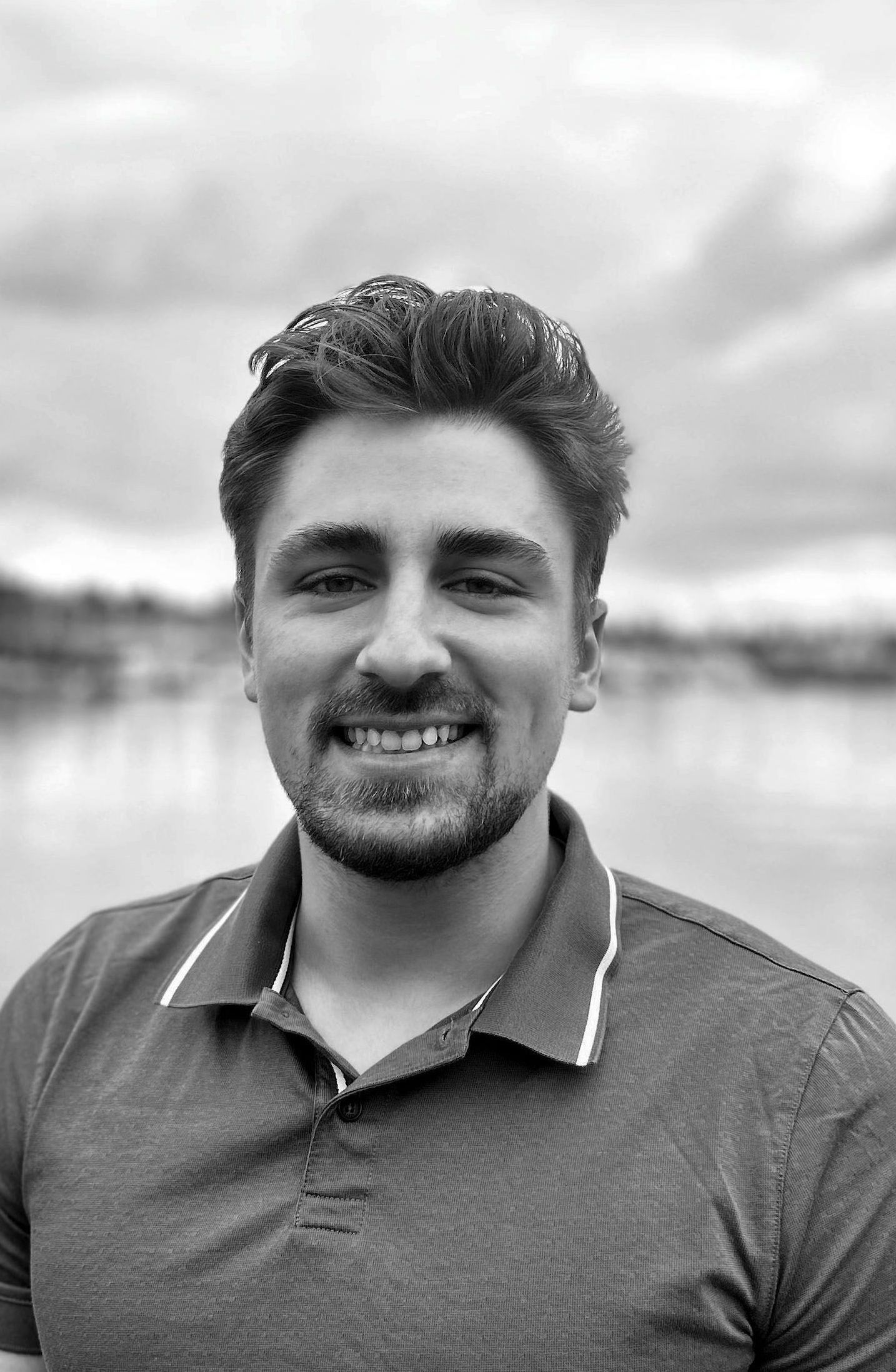 A man with a beard is smiling in a black and white photo.