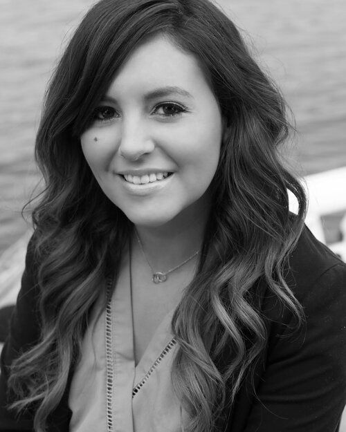 A woman with long hair is smiling in a black and white photo.