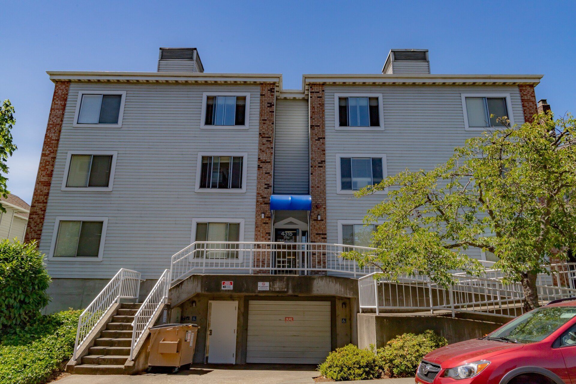 A large apartment building with a red car parked in front of it.