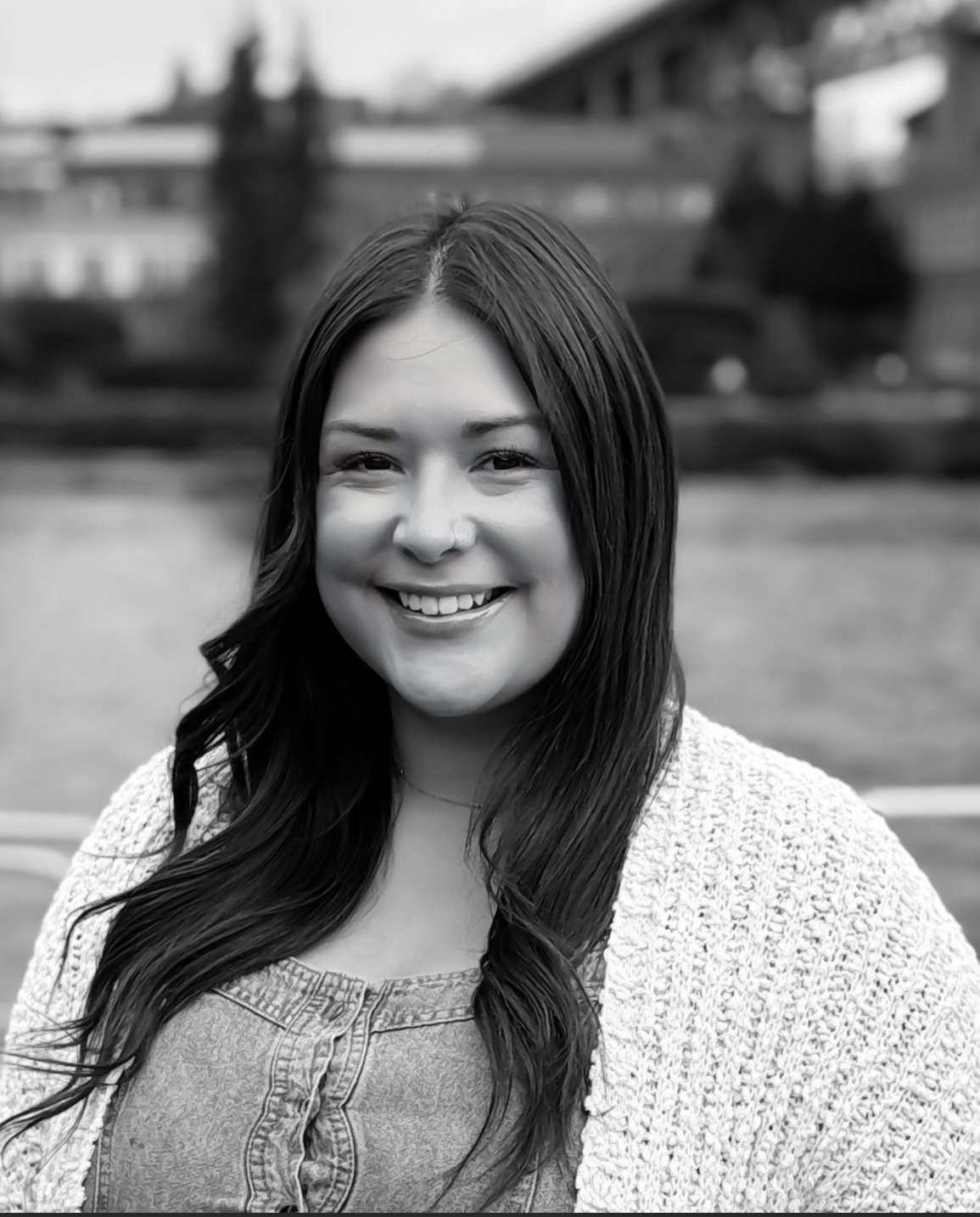 A woman in a white sweater is smiling in a black and white photo.