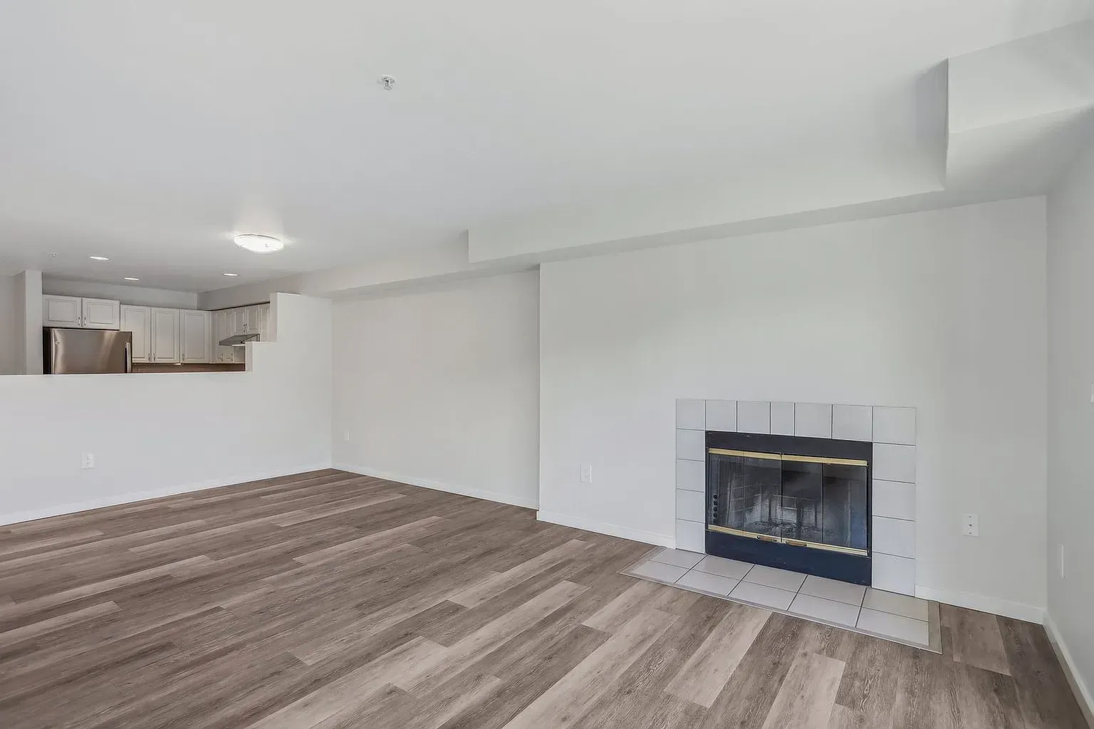 An empty living room with hardwood floors and a fireplace.