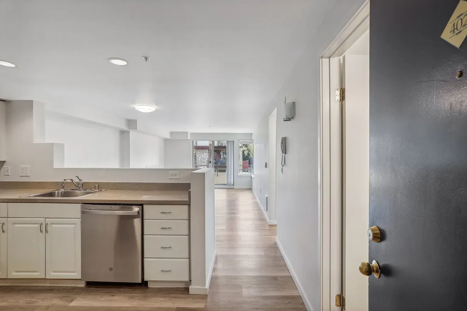A kitchen with white cabinets , stainless steel appliances , a sink and a dishwasher.