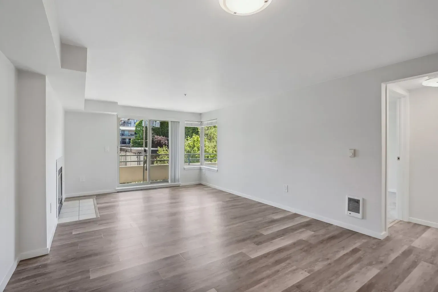 An empty living room with hardwood floors and white walls.
