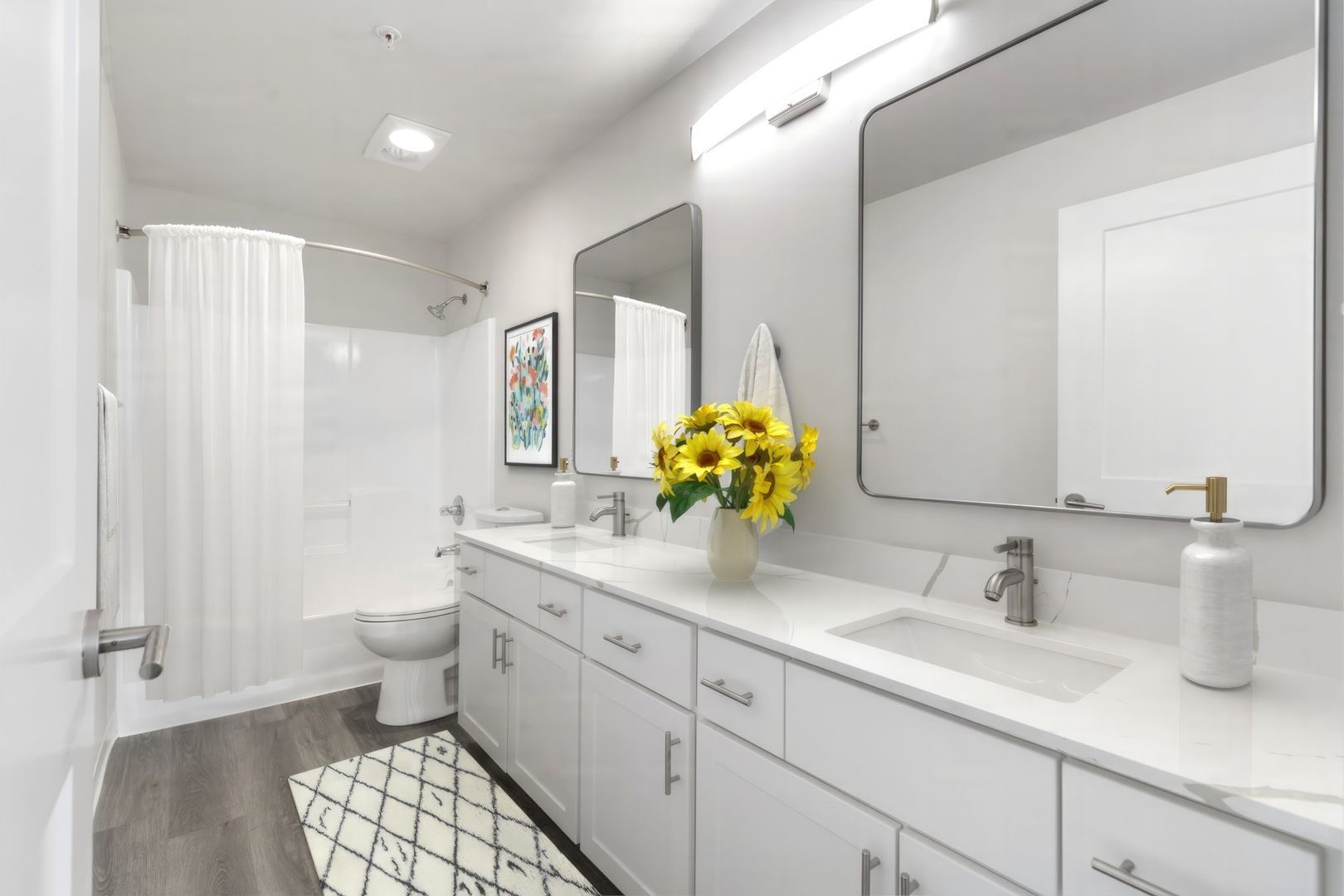 A bathroom with two sinks , a toilet , and two mirrors.