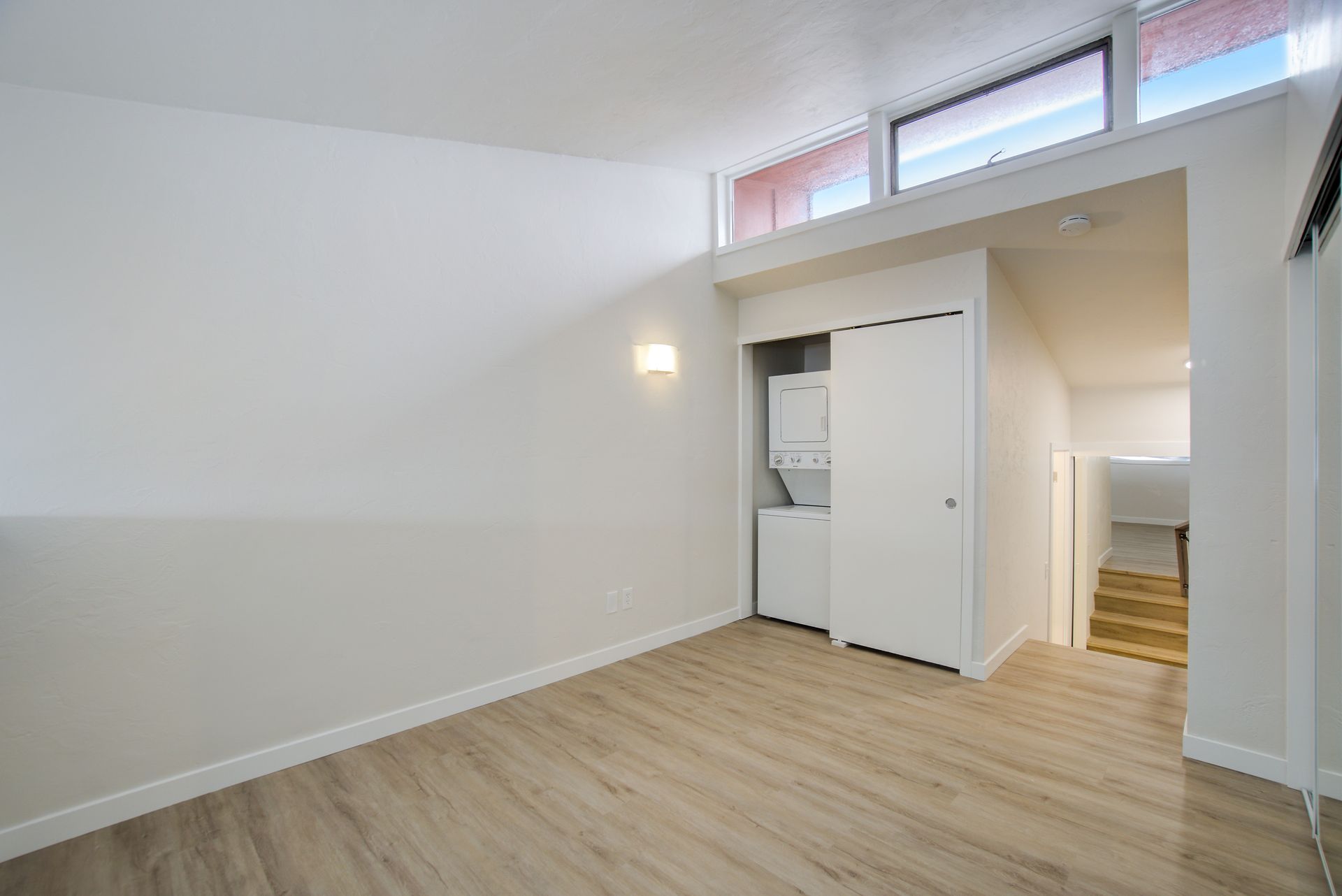 An empty room with a washer and dryer in a closet.