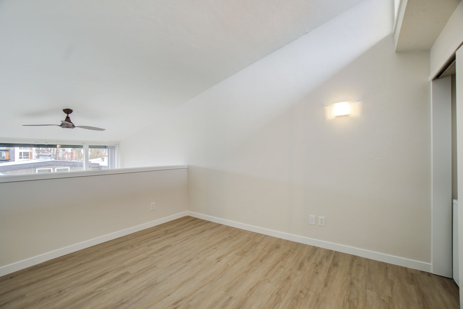 An empty room with a ceiling fan and a window.