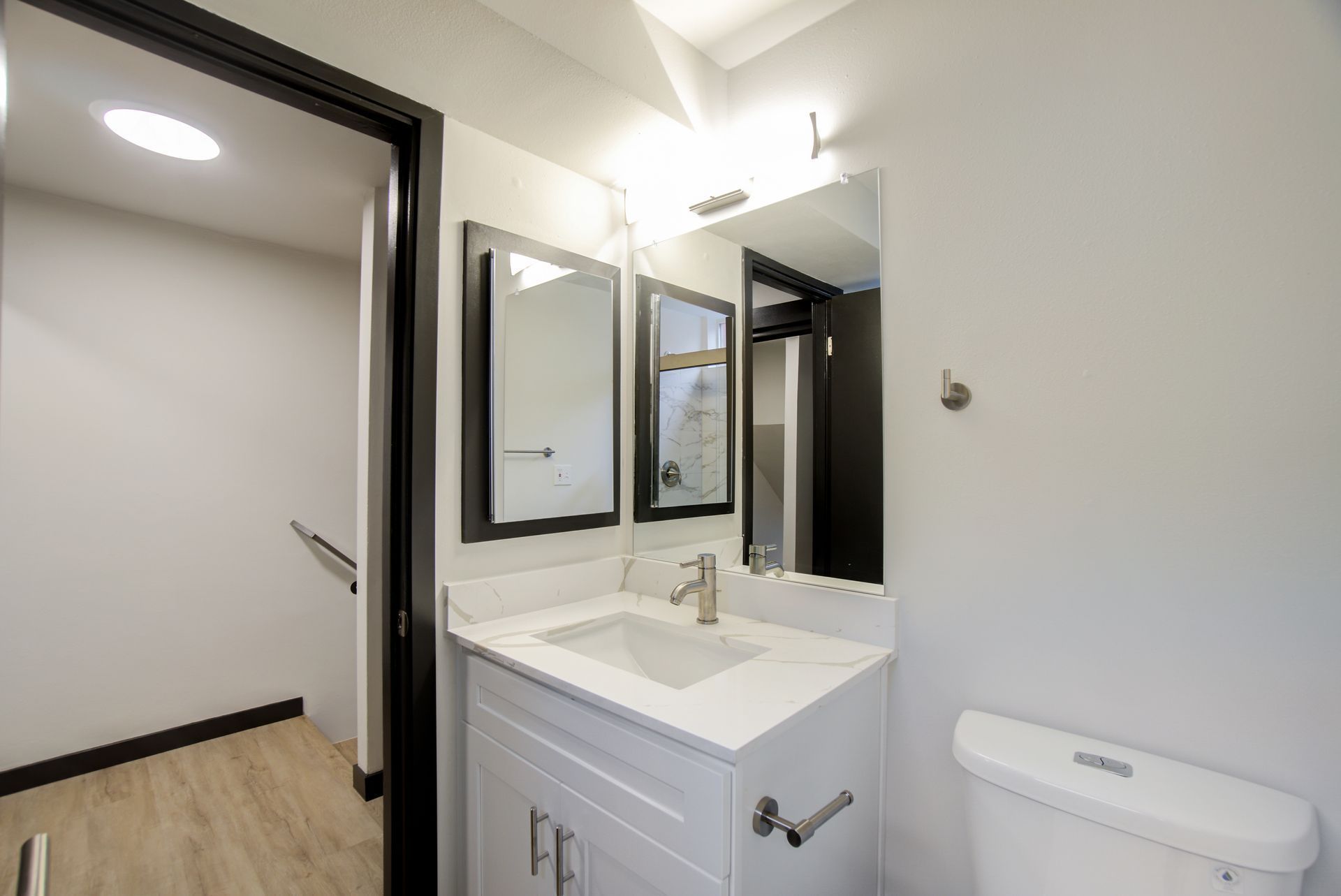 A bathroom with a sink , toilet and mirrors.