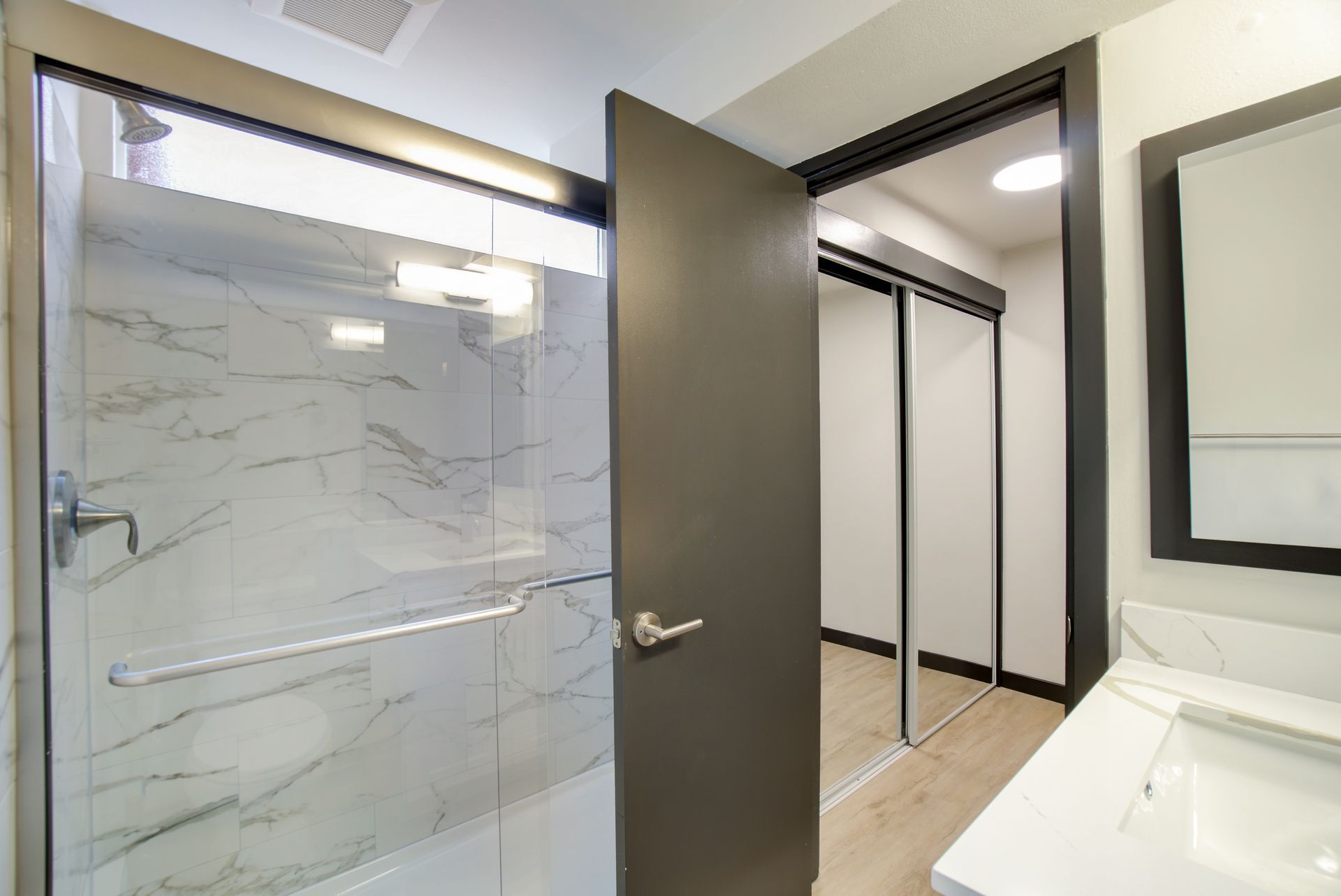 A bathroom with a walk in shower , sink and mirror.
