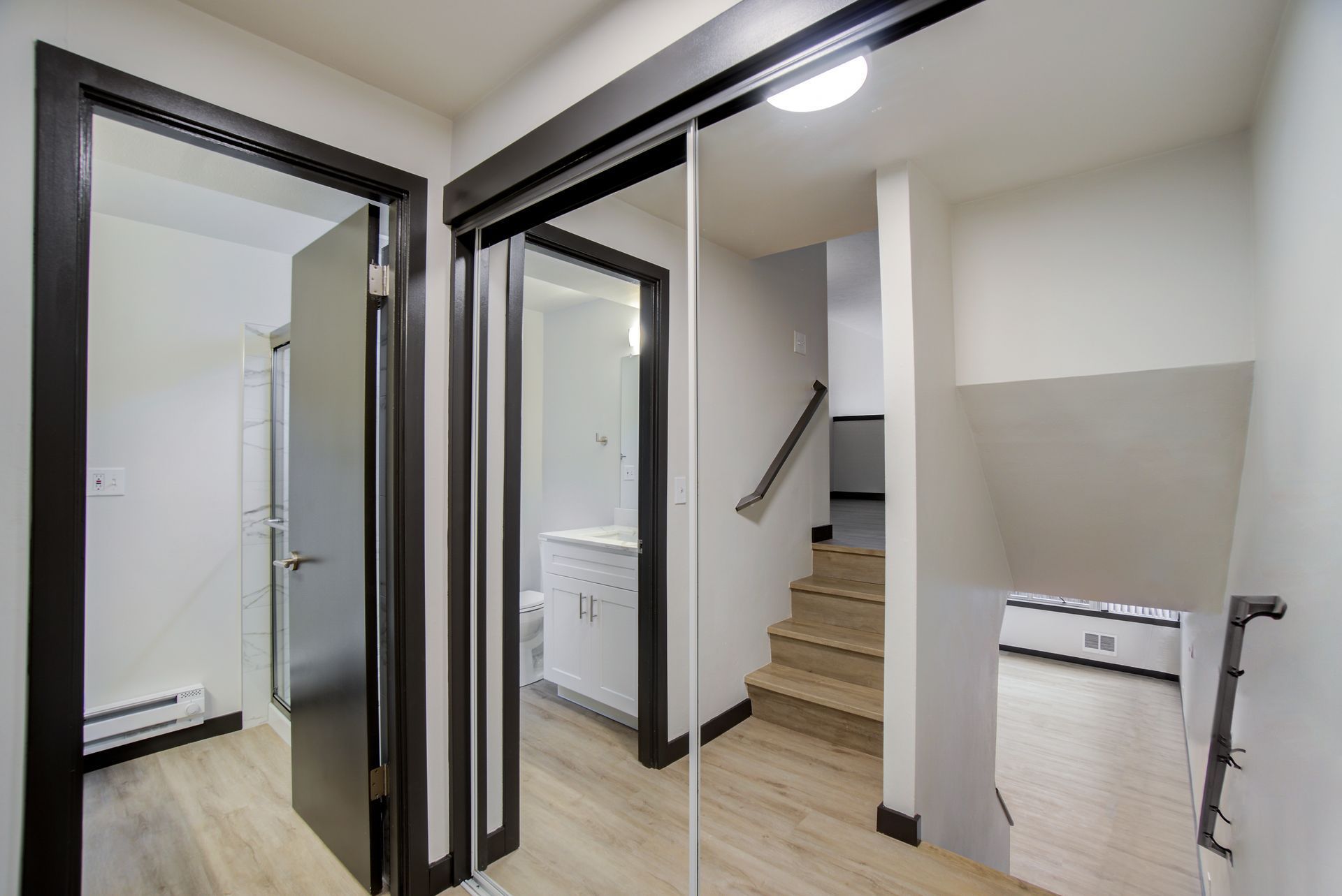A hallway with sliding glass doors leading to a bathroom and stairs.