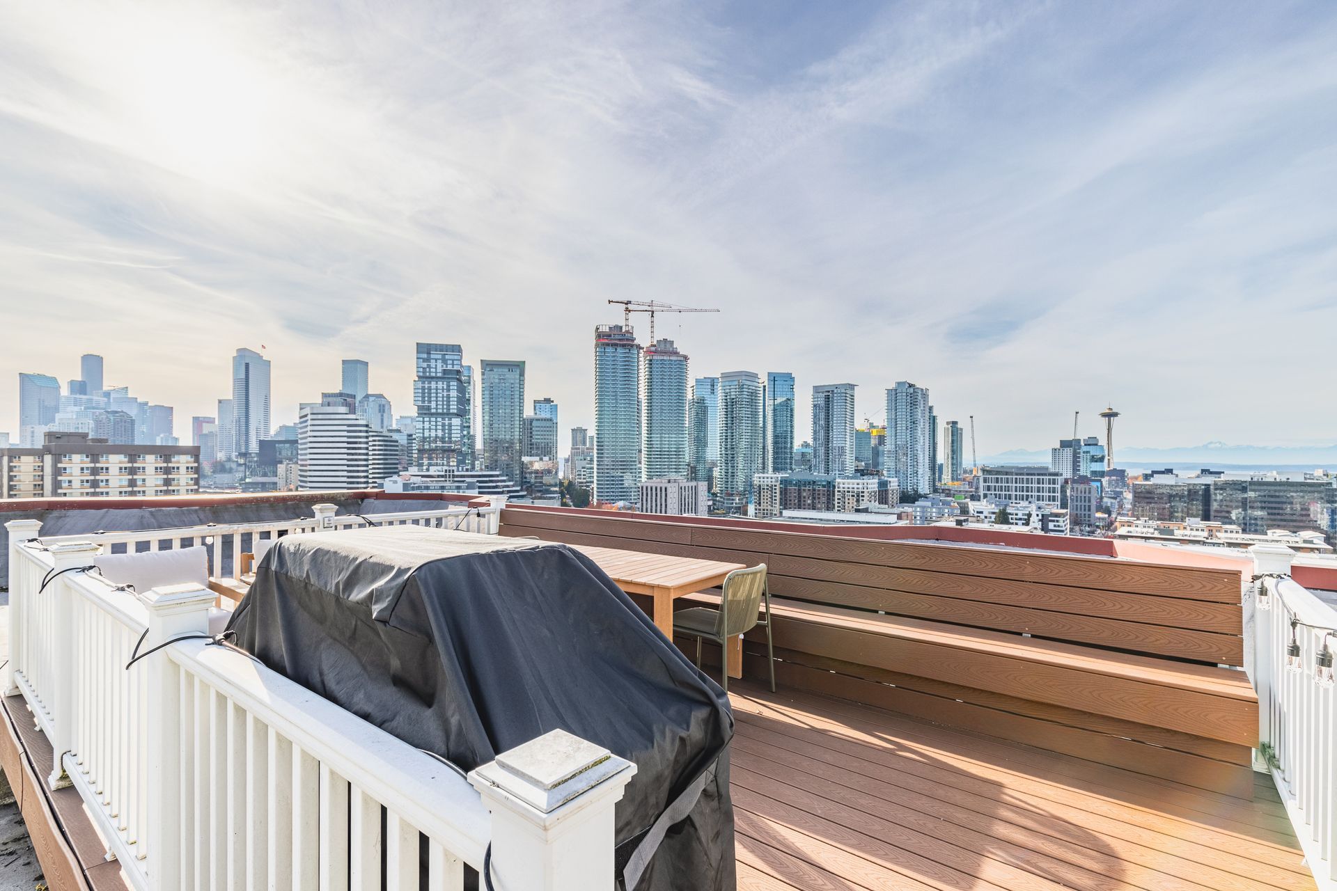 A rooftop deck with a bbq and a view of the city skyline.