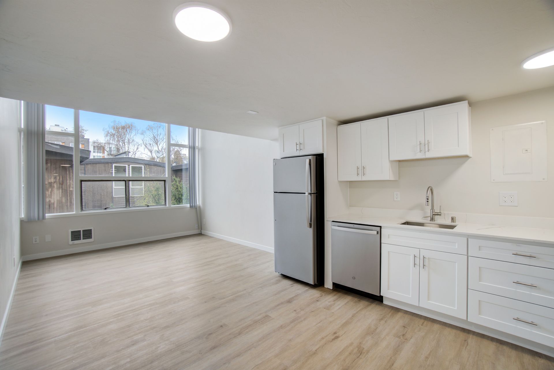 A kitchen with white cabinets , stainless steel appliances and a large window.