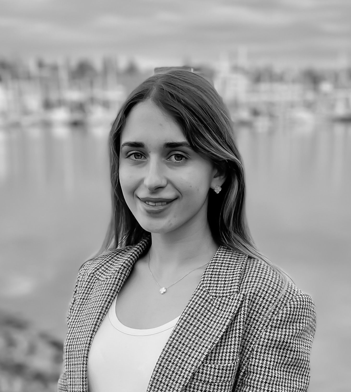 A black and white photo of a woman standing in front of a body of water.