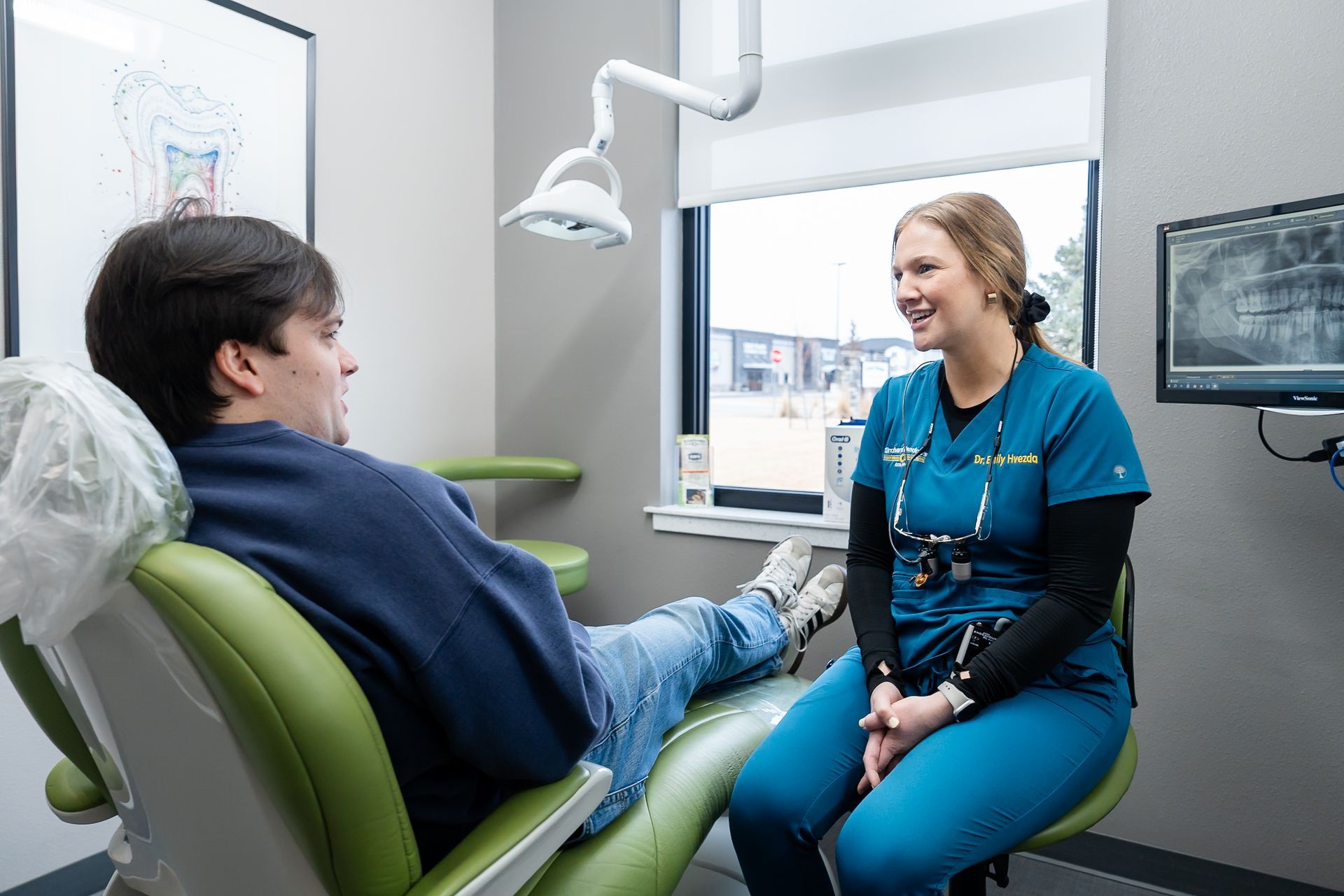 Dentist and patient in a bright dental exam room, smiling during a checkup.