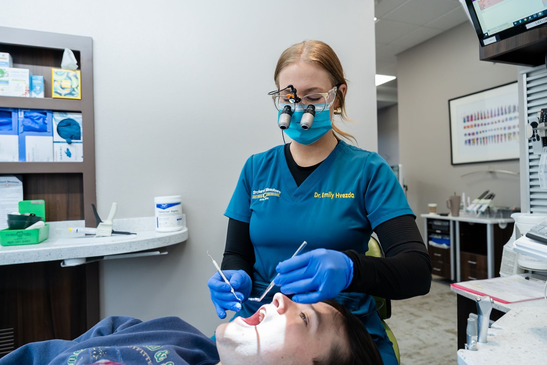 Dentist in blue gloves and mask examines a patient reclining