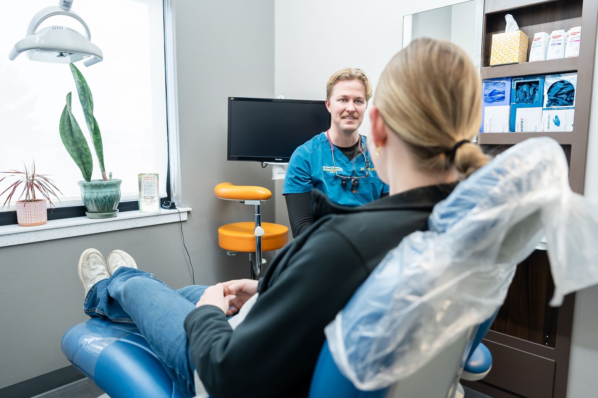Dental patient reclining while dentist consults in a modern clinic office