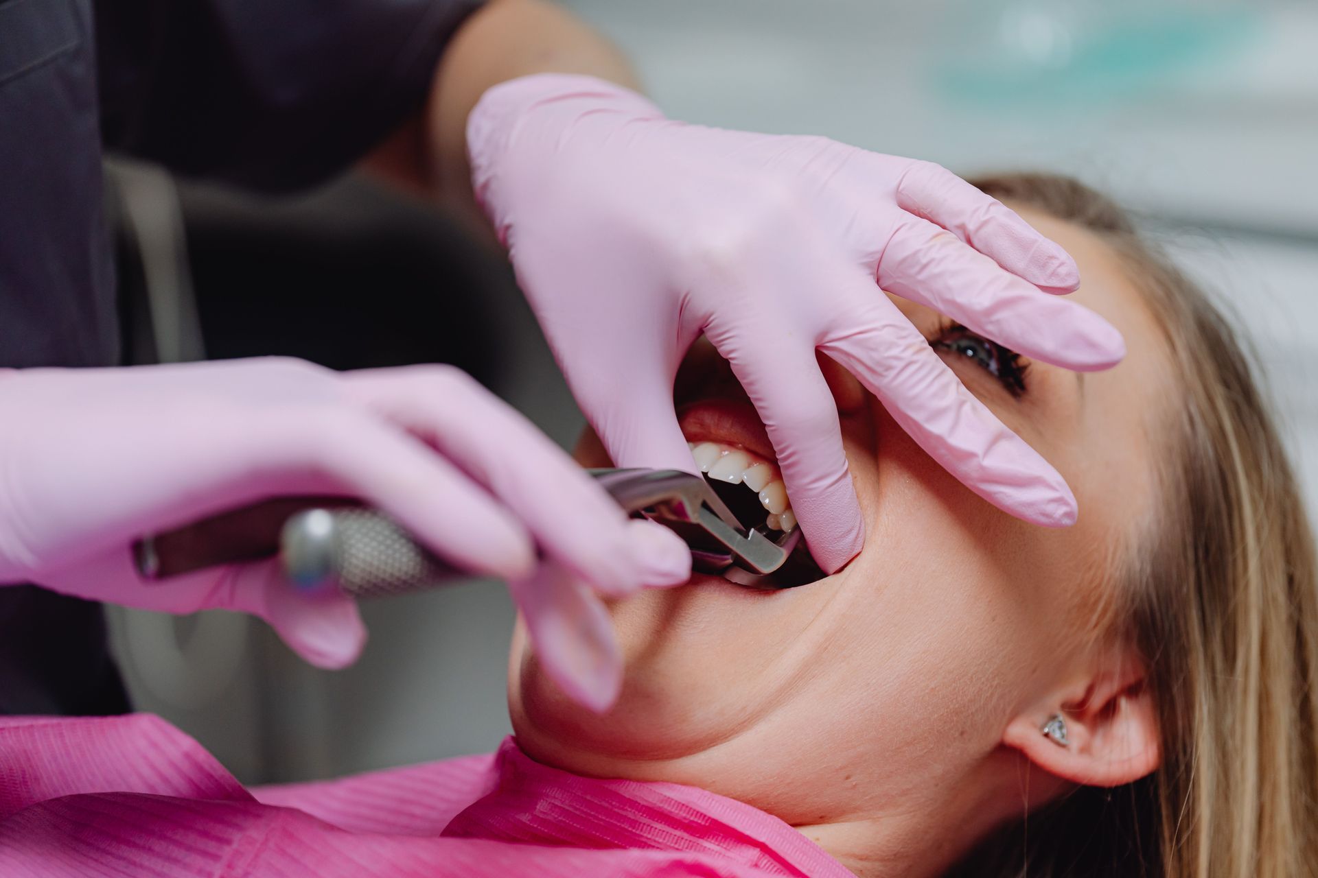 Dentist using gloved hands to examine a patient's open mouth