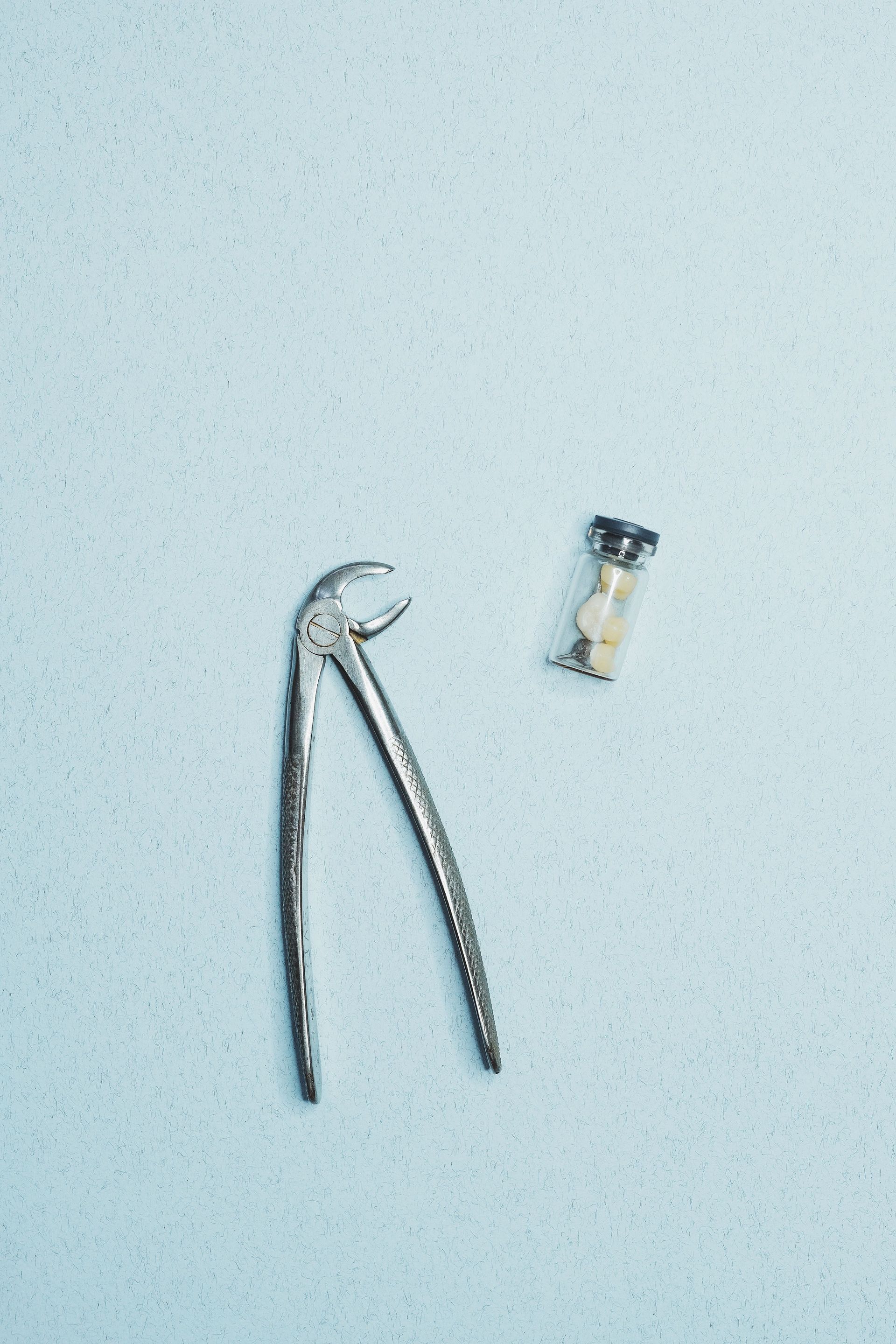 Metal nail clippers and a small screw on a light surface