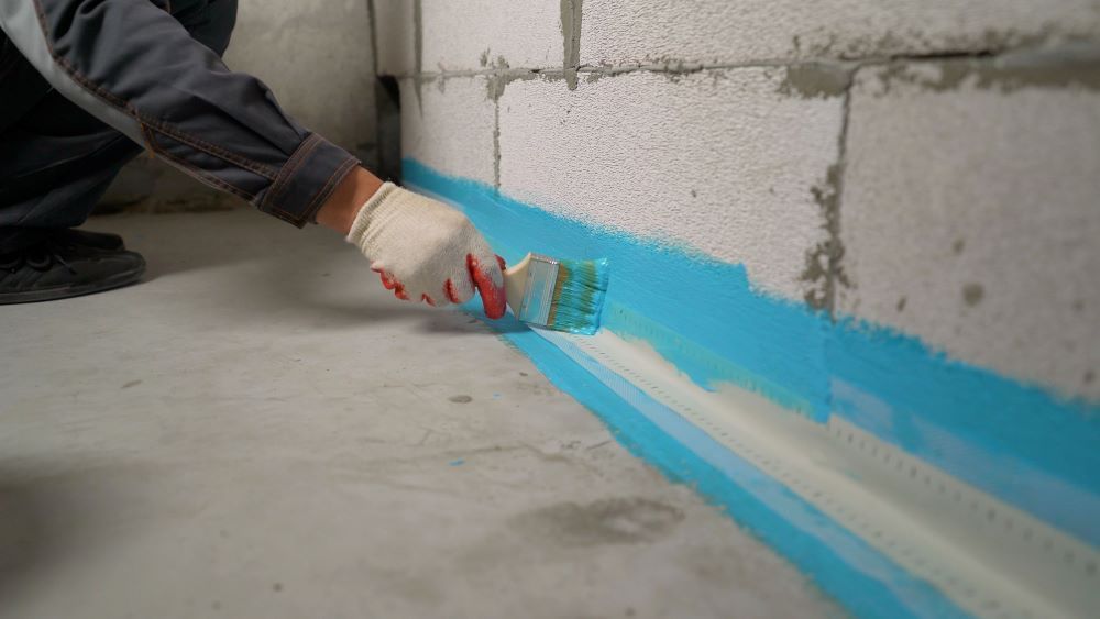 Blue Waterproofing Paint Is Being Applied To The Concrete Wall — Bananacoast Waterproofing in Woolgoolga, NSW
