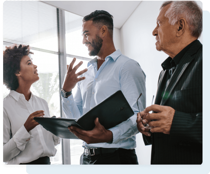 Three business colleagues in an office setting, two women and one man, engaged in a discussion.
