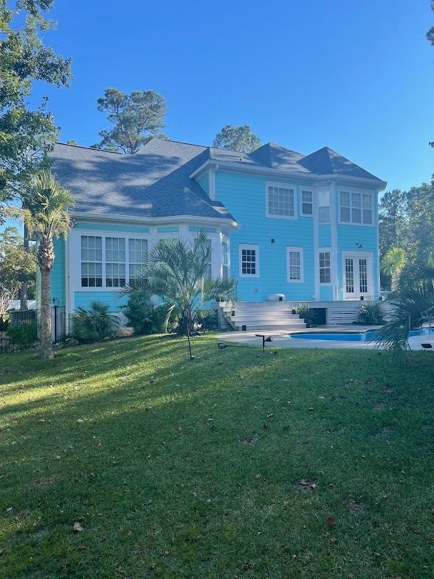 Light blue two-story house with white trim, screened porch, and a sunny front lawn
