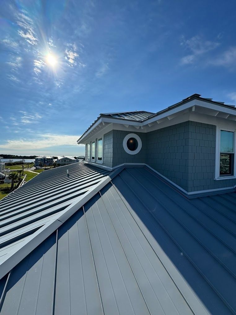 Rooftop deck with blue metal roofing, white trim, and a round window under a bright sky