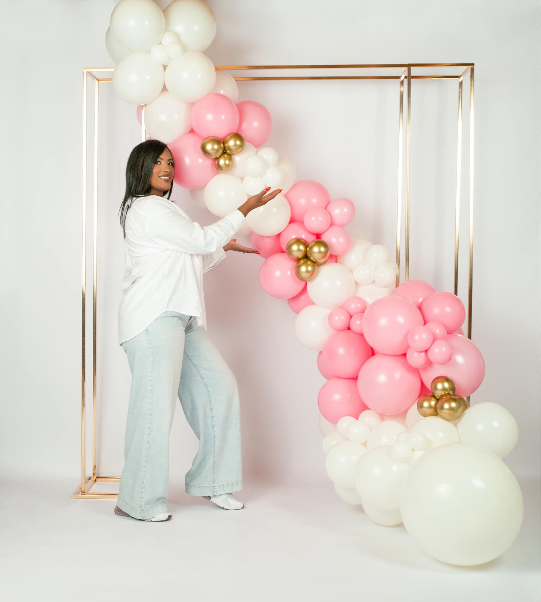 A woman is standing in front of a balloon arch.