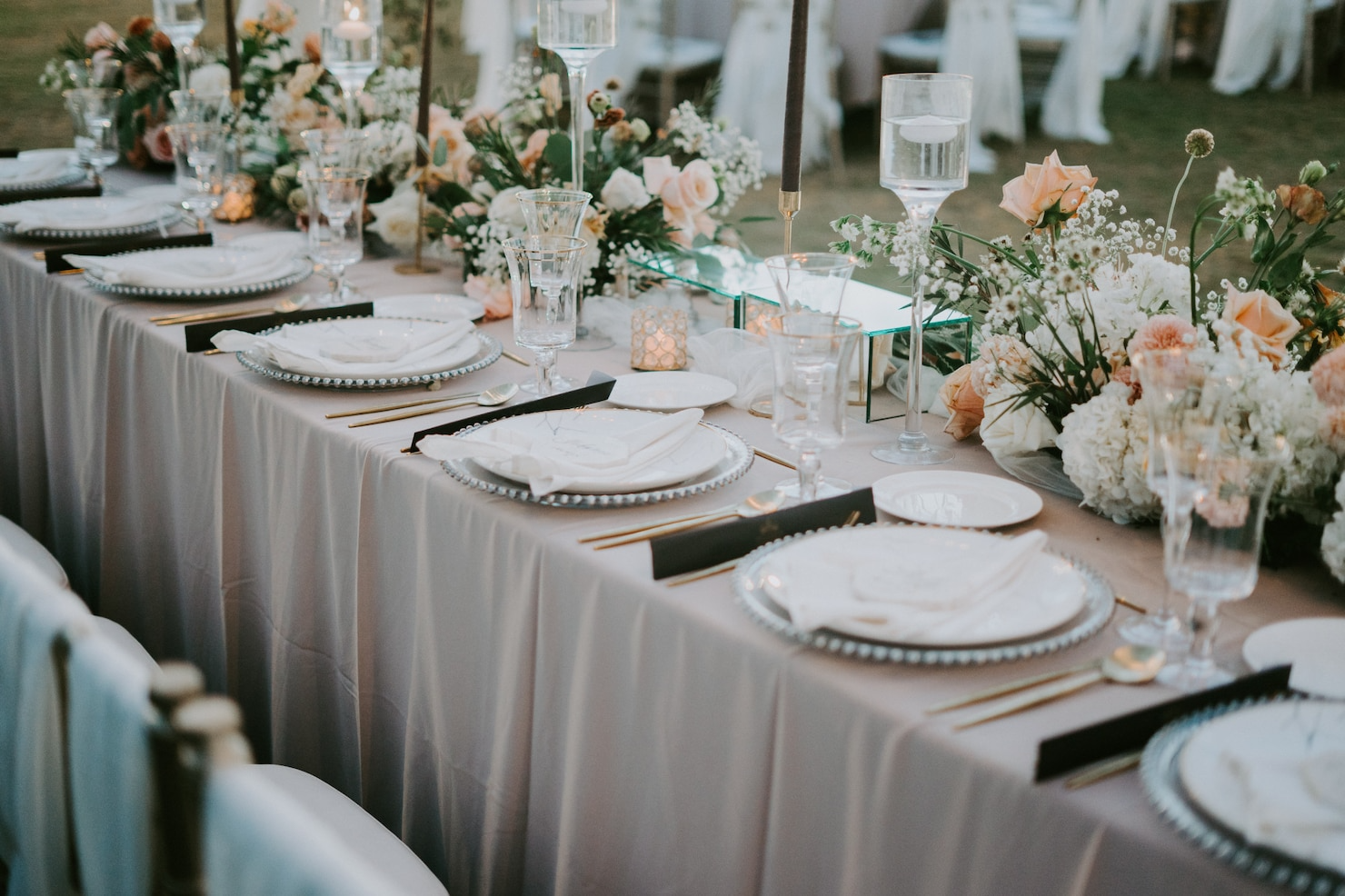 A long table with plates , glasses , and flowers on it.